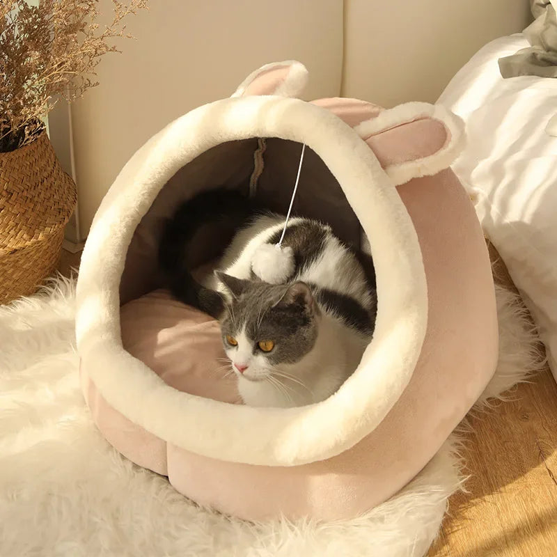 Cozy pink cat bed with bunny ears, featuring a gray and white cat inside, perfect for pet comfort.