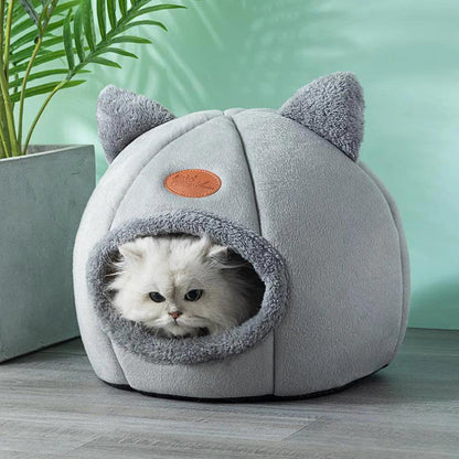 Cozy gray cat cave bed with fluffy white cat peeking out, perfect for indoor pet comfort and sleep.