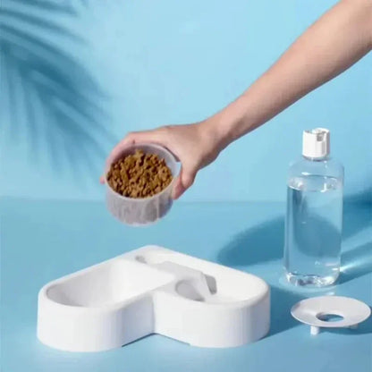 Hand pouring dry dog food into white elevated pet feeder with water bottle beside, ideal for cats and dogs